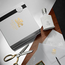 Creed Silver Mountain Water Parfum mit Geschenkbox, Schere und Karte auf Holztisch arrangiert