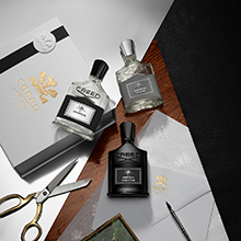 Creed Aventus Duftkollektion mit mehreren Parfumflakons und Geschenkbox auf elegantem Tisch arrangiert