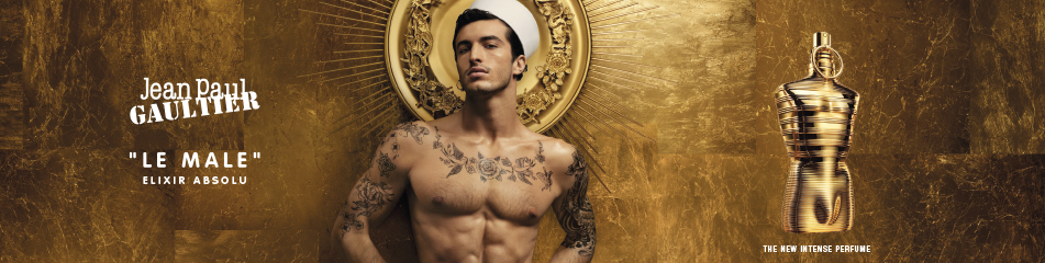 Jean Paul Gaultier Le Male Elixir Absolu Werbekampagne mit einem muskulösen, tätowierten Mann in Matrosenmütze vor goldener Aura, neben dem glänzenden, goldenen Parfumflakon.