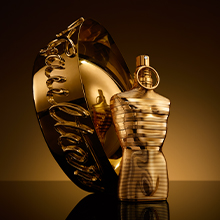 Jean Paul Gaultier Le Male Elixir Absolu Eau de Parfum in goldener, männlich geformter Flasche neben passender goldener ovaler Dose mit verschnörkeltem Schriftzug.
