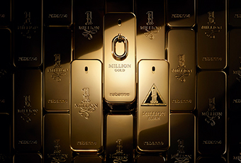 Goldene Parfumflakons in Form von Barren, eng aneinandergereiht. In der Mitte hebt sich ein Flakon mit graviertem Ringverschluss und der Aufschrift 'Million Gold' hervor. Umgeben ist er von weiteren Flakons mit verschiedenen Gravuren, darunter '1 Million' und das Rabanne-Logo.